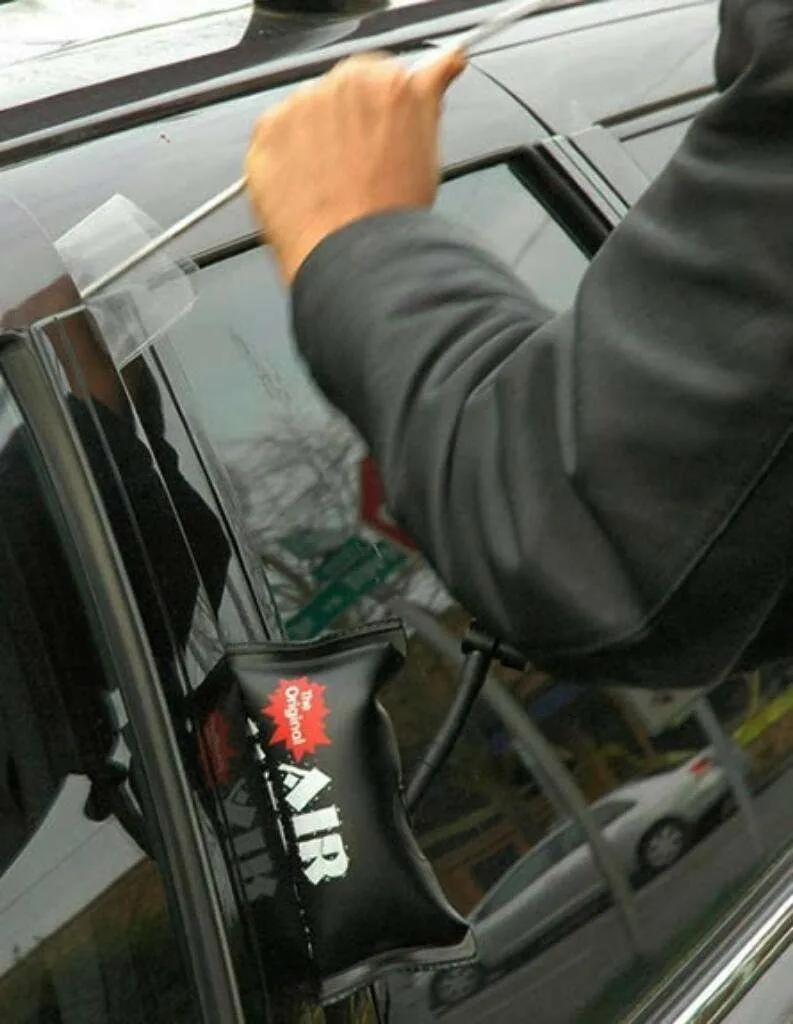 Cerrajero abriendo la puerta de un carro con una cuña de aire en el marco de la ventana.