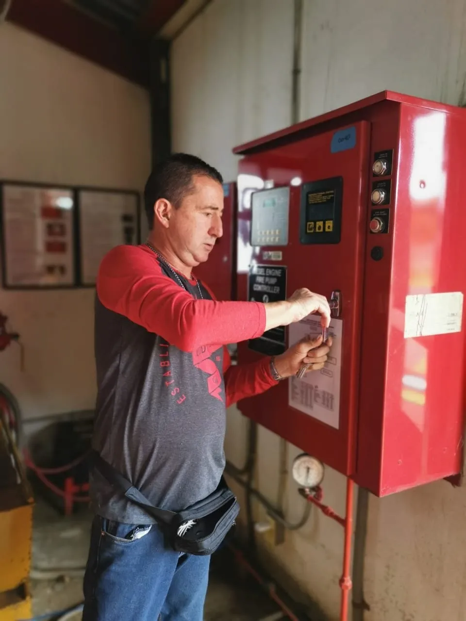 Técnico trabajando en una caja fuerte roja con teclado digital.