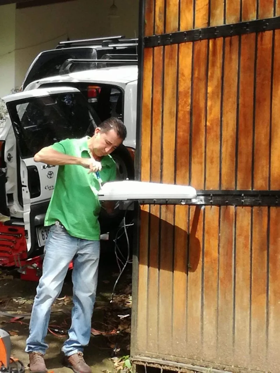Técnico instalando el brazo de un motor de pistones en un portón de madera.